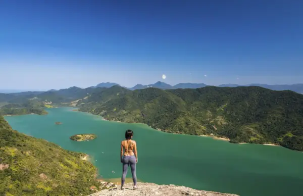 Frauenblick auf die grüne Bucht von Paraty, Brasilien, mit bewaldeten Bergen und Inseln.