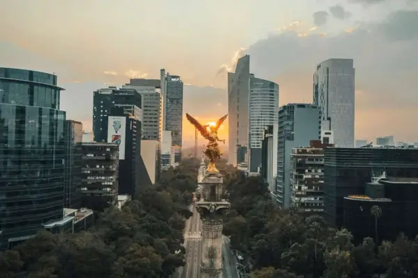 Goldene Viktoria-Statue im Sonnenuntergang, umgeben von modernen Wolkenkratzern in Mexico City.
